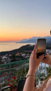 a woman taking a picture of the sunset with her cell phone at HORIZONT Rooms in Lukovë