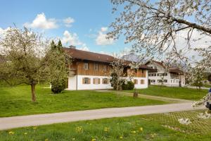 a building with a green lawn and a dirt road at Mayerbauer in Piding