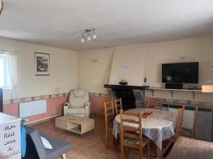 a living room with a table and a tv at Gîte de L'embarcadère in Moustéru