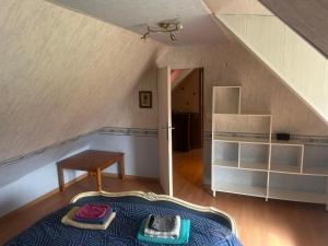 an attic room with a bed and a table at Gîte de L'embarcadère in Moustéru