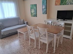 a living room with a table and chairs and a couch at Apartamentos Cala Llonga in Cala Llonga