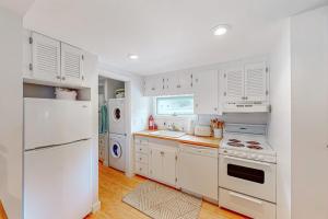 a white kitchen with white appliances and white cabinets at Yellow Door Cottage in Meredith +21 photos