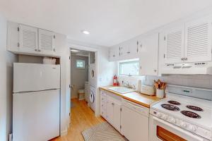 a kitchen with white cabinets and a white refrigerator at Yellow Door Cottage in Meredith