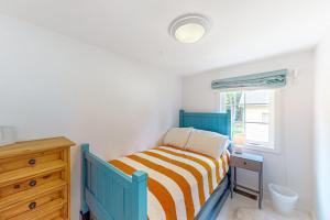 a bedroom with a bed and a dresser and a window at Yellow Door Cottage in Meredith