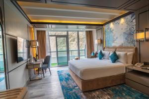 a hotel room with a large bed and a desk and a desk at Pearl Continental Attabad Lake, Hunza in Hunza Valley