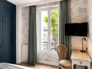 a bedroom with a window and a desk and a chair at Hotel des Bains in Paris