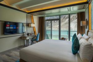 a hotel room with a large bed and a desk at Pearl Continental Attabad Lake, Hunza in Hunza Valley