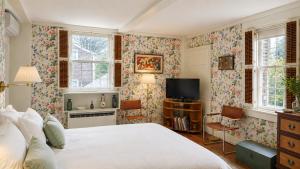 a bedroom with a bed and a tv and windows at 29 India House in Nantucket