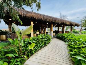 a pathway leading to a resort with a thatched roof at Luxe Gold Mactan in Mactan