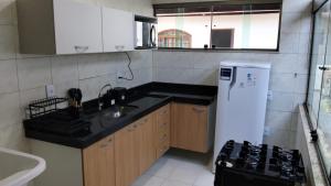 a small kitchen with a sink and a refrigerator at Casa da Dinda 104 in Rio das Ostras +2 photos