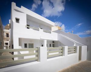a white house with a fence and blue sky at Ione Inn in Naxos Chora