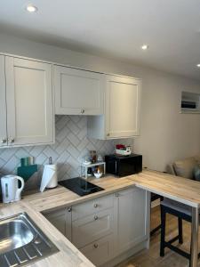 a kitchen with white cabinets and a counter top at Holyport Studio flat in Bray