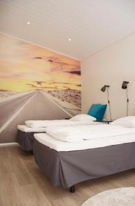 twee bedden in een kamer met een schilderij aan de muur bij Autokeidas Forssa Motelli in Forssa +9 foto's