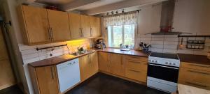 a kitchen with wooden cabinets and a sink and a stove at Lægran Gård in Steinkjer