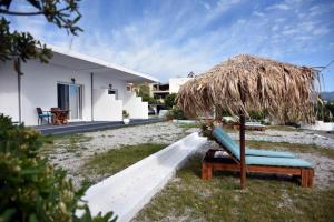 a chair under a straw umbrella next to a house at Soultana’s house in Mourteri