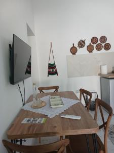 a wooden table with chairs and a tv on a wall at Guest House Nino's in Çorovodë