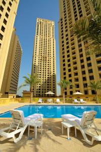 ein Pool mit zwei Stühlen und zwei hohen Gebäuden in der Unterkunft Suha JBR Hotel Apartments in Dubai