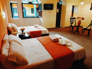 a hotel room with two beds and a tv at Casona del Inca Cajamarca in Cajamarca