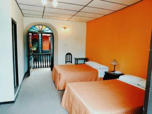 two beds in a room with orange walls at Casona del Inca Cajamarca in Cajamarca +6 photos