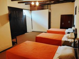 a hotel room with three beds and a closet at Casona del Inca Cajamarca in Cajamarca