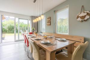 a dining room with a long wooden table and chairs at Hoogelandt 106F in De Koog