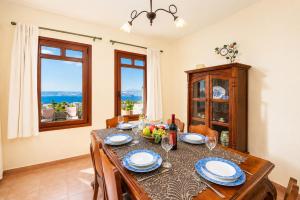 a dining room with a table and chairs and windows at Villa Aphrodite in Plaka