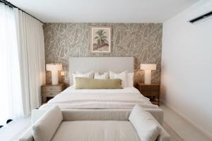 a bedroom with a large white bed with a couch at Stylish West Coast 3BR Retreat with Pool Near Beach in Saint James