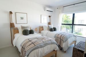 two beds in a bedroom with white walls and a window at Stylish West Coast 3BR Retreat with Pool Near Beach in Saint James +27 photos