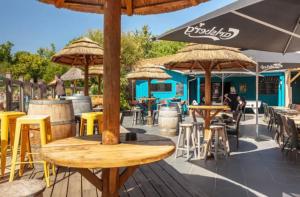 an outdoor patio with tables and chairs and umbrellas at La Cabane du Lac - Biscarrosse 5 étoiles in Biscarrosse