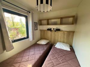 two beds in a small room with a window at La Cabane du Lac - Biscarrosse 5 étoiles in Biscarrosse