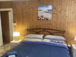 a bedroom with a blue bed and wooden walls at Logudoro Cabin by Holiday World in Alghero