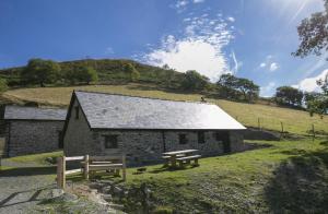 a small stone building with two picnic tables in front of it at Cwm Clyd Longhouse in Llanwrthwl +4 photos