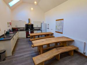a kitchen with two wooden tables and a kitchen with a counter at Cwm Clyd Longhouse in Llanwrthwl