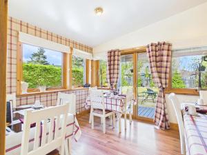 a dining room with a table and chairs and windows at Dunroamin Bed and Breakfast in Aviemore