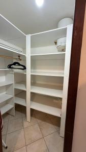 a closet with white shelves in a room at Peace's House, Studio moderne, Bas-du-Fort, Plage à pied, Parking privé in Le Gosier