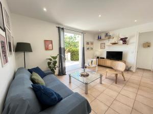 a living room with a blue couch and a table at Adorable maison de vacances plain pied au coeur de la station et proche des plages 4 chambres, jardin, WIFI, LXDUNE1 in Portiragnes