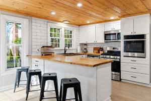 a kitchen with white cabinets and a wooden ceiling at Charming Kennebunk Cape - Walk to Dock Square! in Kennebunk