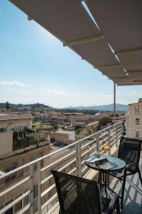 a balcony with two chairs and a table with a view at 24K Athena Suites in Athens