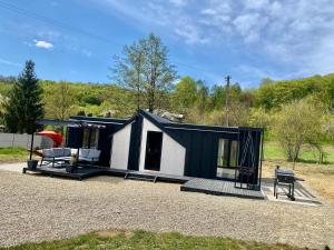 a black and white tiny house with a porch at Wood Retreat in Valea Bradului