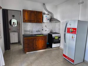 a kitchen with wooden cabinets and a white refrigerator at Departamento Don Nico in San José de la Dormida