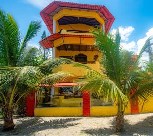 a yellow building with two palm trees in front of it at Hotel Cielo Azul in Atacames