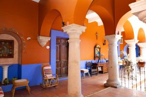 a room with orange walls and columns and a dining room at Casa de Siete Balcones Hotel Boutique in Oaxaca City