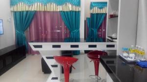 a dining table with two red stools in a room at SAS D'PERDANA Apartment in Kota Bharu