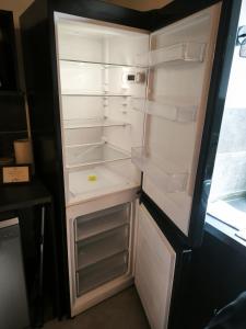 an empty refrigerator with its door open in a kitchen at Studio des 3 bassins in La Chapelle-Blanche