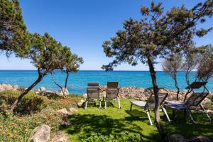 a group of chairs sitting on the grass near the ocean at B&b Giglio di Mare in Cala Liberotto