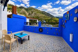 a blue walled balcony with a table and a chair at Riad Zaitouna Chaouen in Chefchaouen