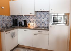 a kitchen with white cabinets and a microwave at La villa Margats - Charme & détente en bord de mer in Bray-Dunes