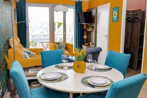 a dining room with a table and blue chairs at La villa Margats - Charme & détente en bord de mer in Bray-Dunes