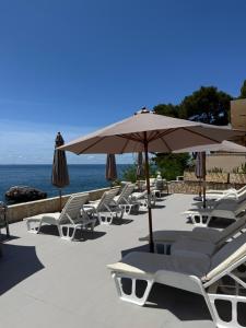 a row of lounge chairs and an umbrella and the ocean at Suites Castello in Bar
