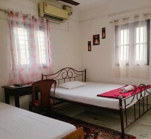 a bedroom with two beds and a desk and windows at Ebenezer Stay in Trivandrum
